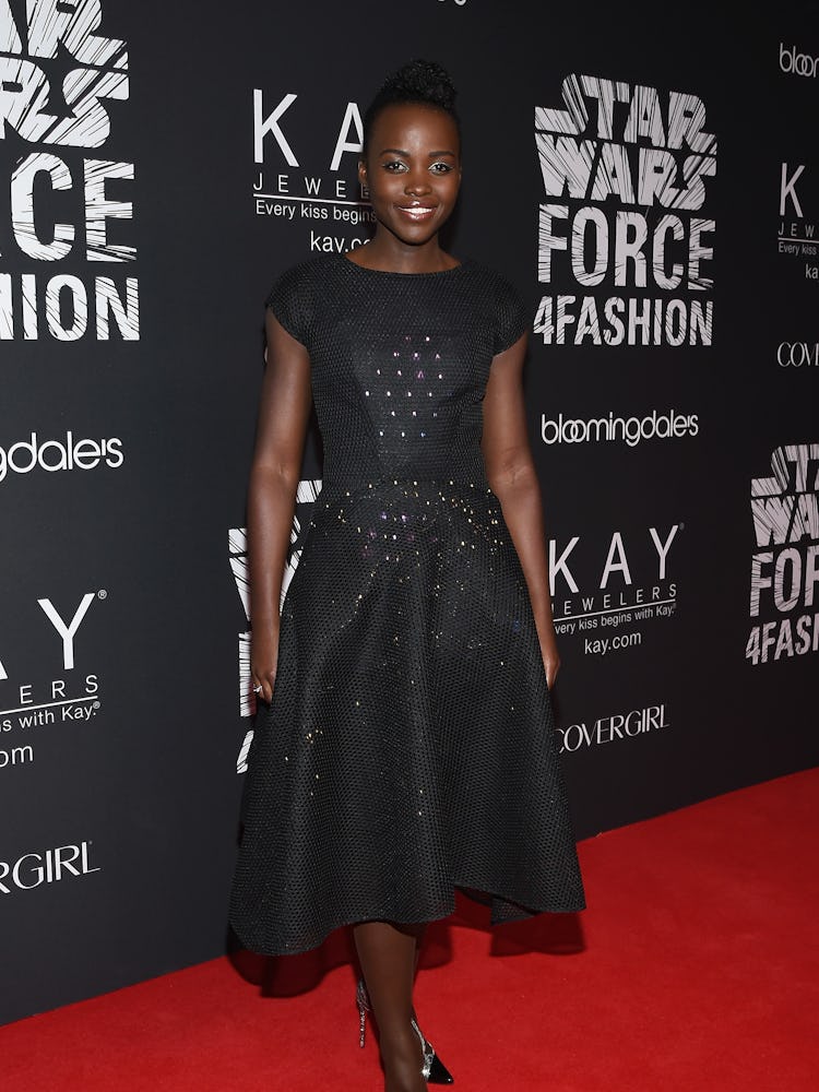 Lupita Nyong’o posing while wearing a black dress