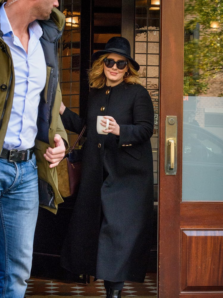Adele walking while wearing a black Burberry coat