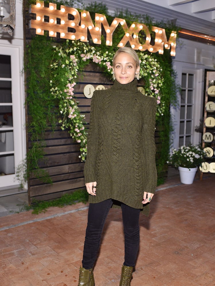 Nicole Richie posing while wearing a green shirt and black pants