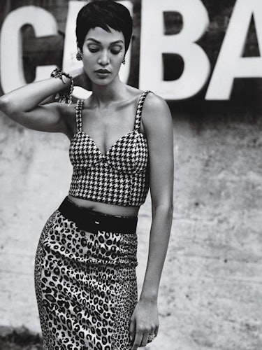 A female model posing while wearing a plaid combination of a bralette and skirt