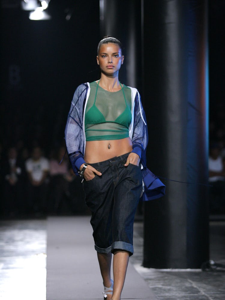 Adriana Lima walking the runway in sheer green top and baggy denim trousers during Sao Paolo Fashion...