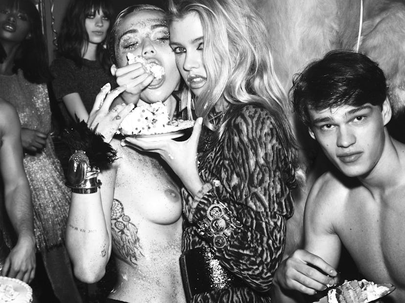 Miley Cyrus topless being fed cake by a woman and two men next to them at her party