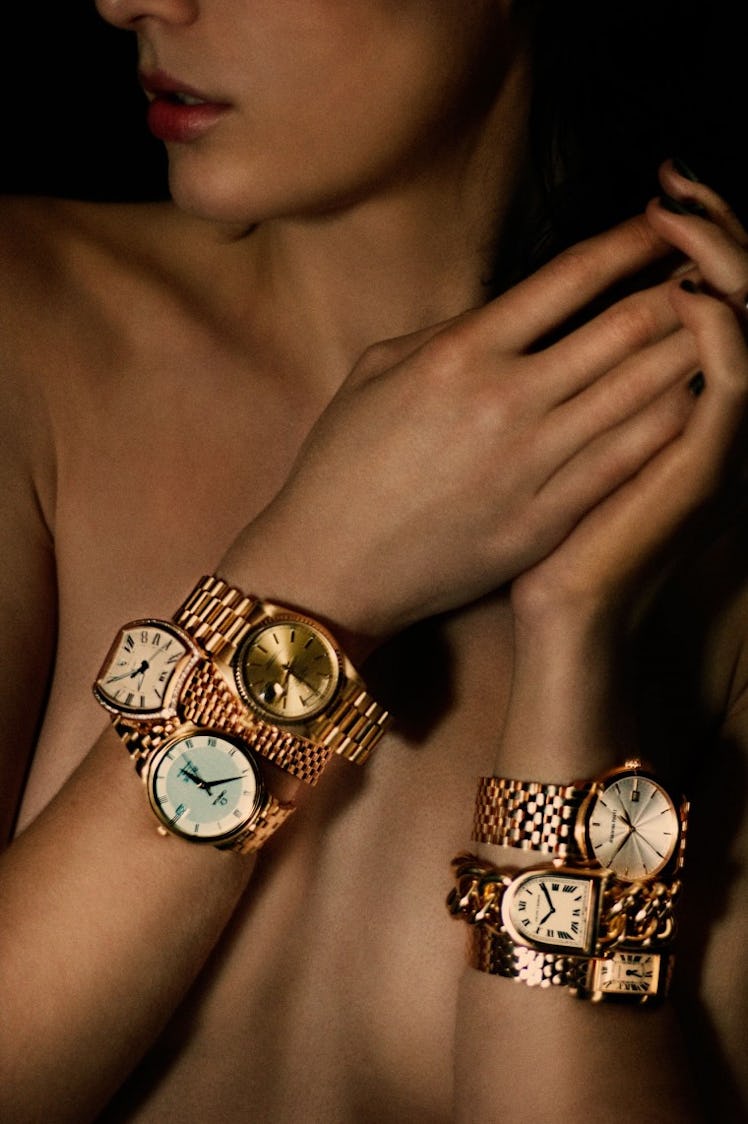 A woman posing for a photo while wearing six golden watches in her hands