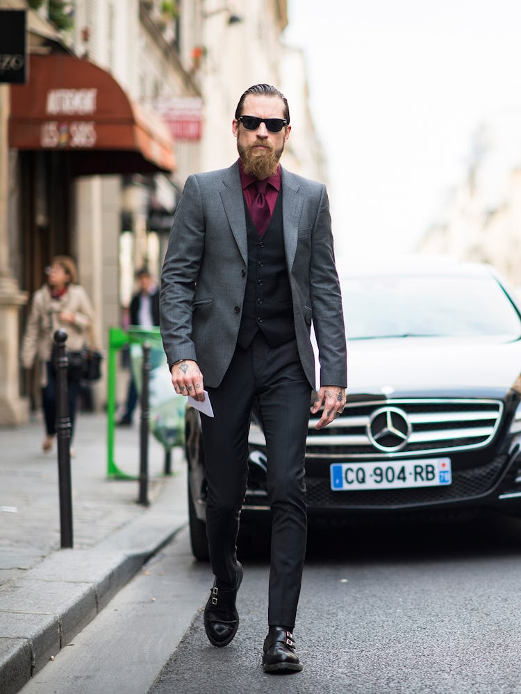 Justin O’Shea walking while wearing a formal suit at the 2013 Paris Men’s Fashion Week