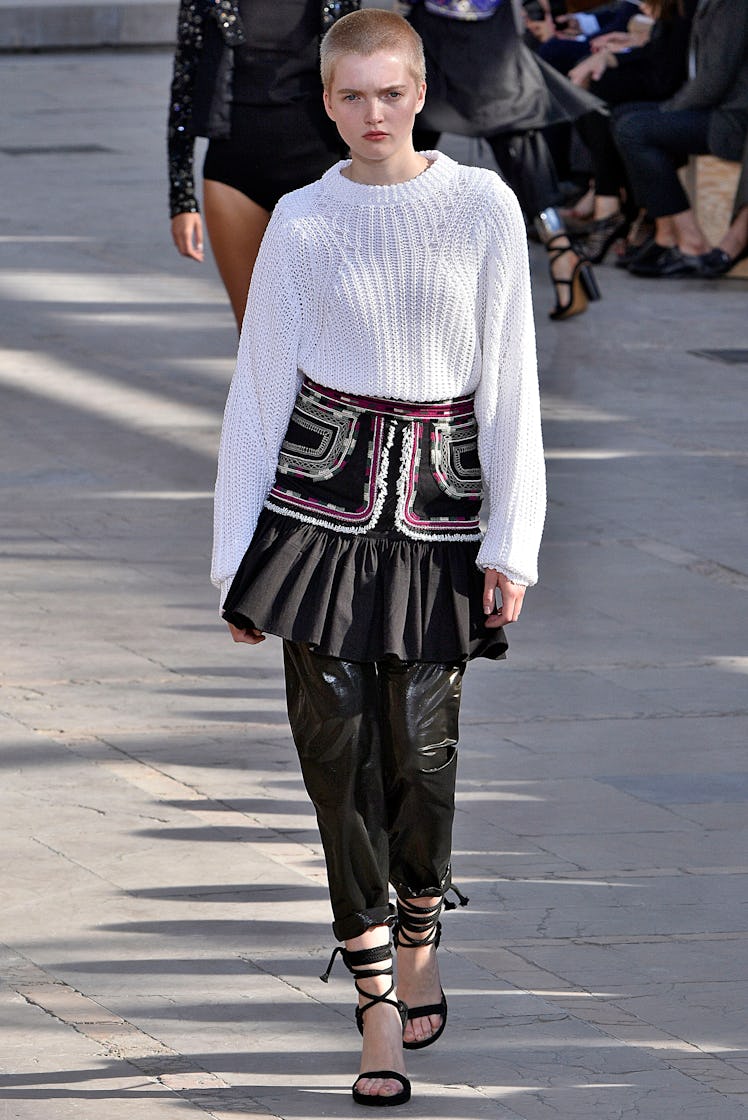 Ruth Bell walking down the runway while wearing a white sweater and a black skirt over a black pants...
