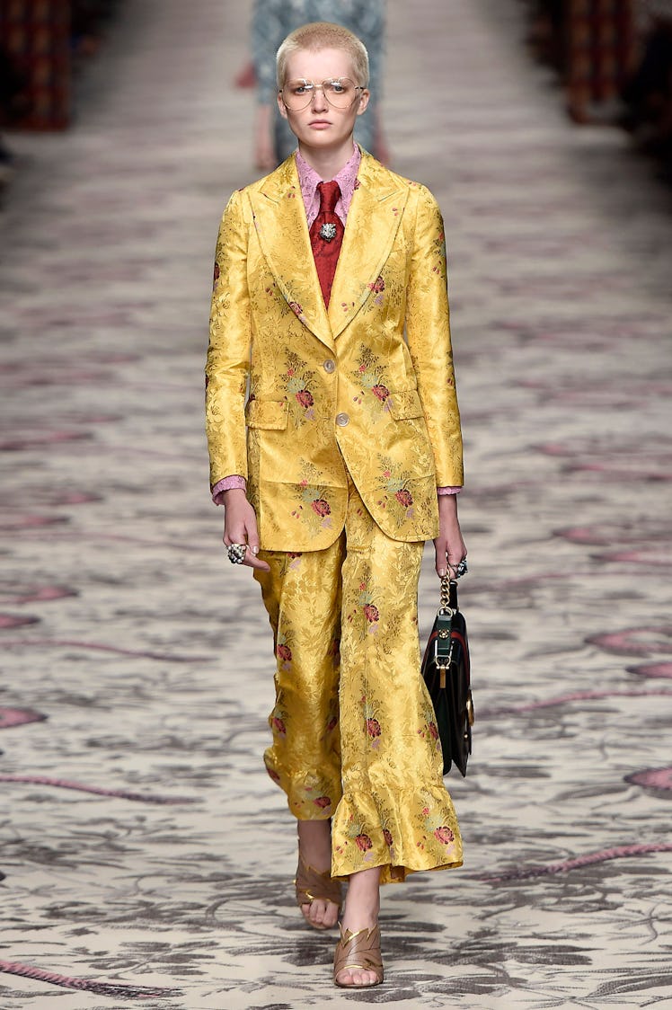 Ruth Bell walking down the runway in a yellow Gucci suit with floral details at Milan Fashion Week S...