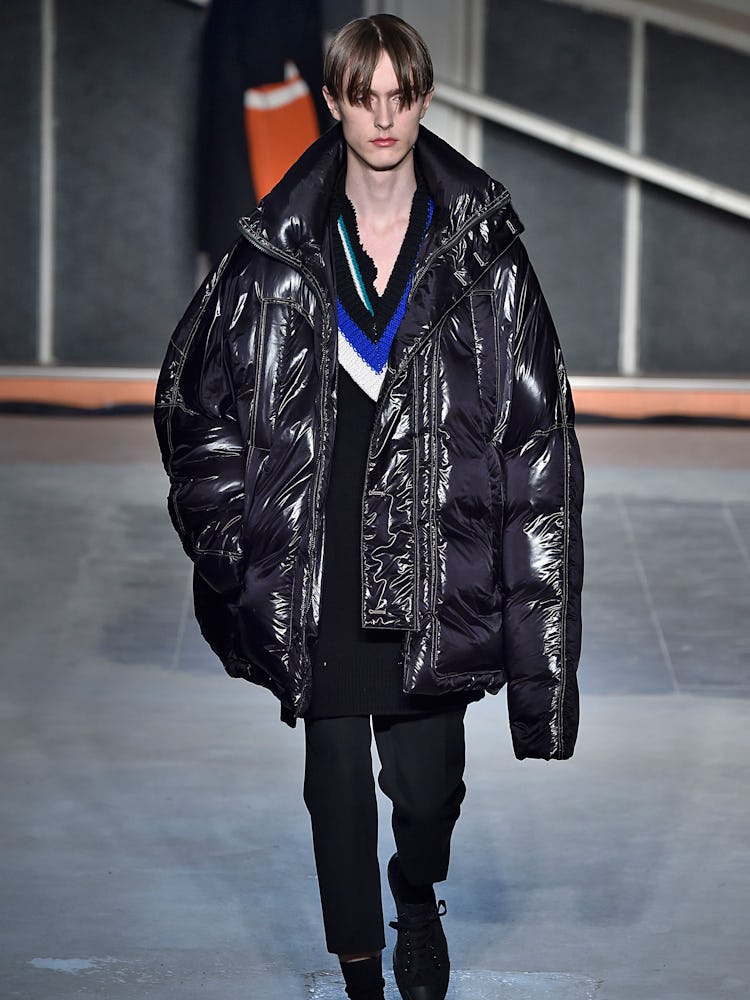 A model walking the runway in an oversized black jacket during Raf Simons Fall 2016 fashion show in ...