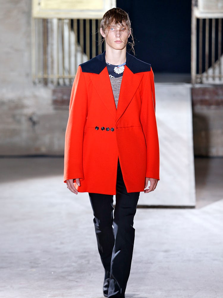 A model wearing a red coat with black details from Raf Simons' Spring 2015 lineup