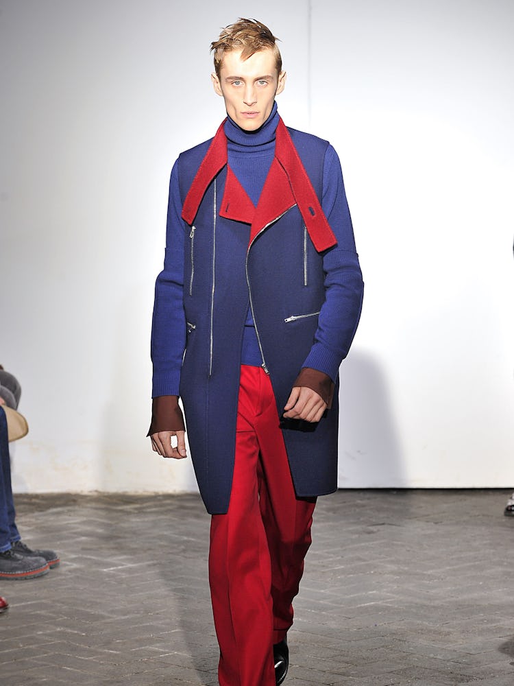 A model wearing a red-and-blue suit during Raf Simons' Fall 2013 fashion show in Paris