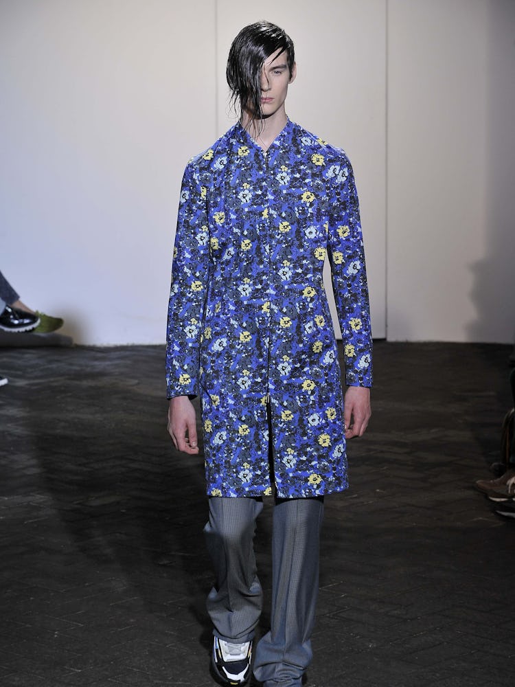 A model walking the runway in a blue floral shirt from Raf Simons' Spring 2013 collection
