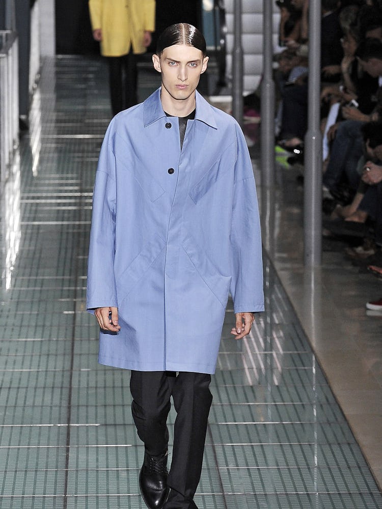A model walking the runway in a blue coat from Raf Simons Spring 2012 line