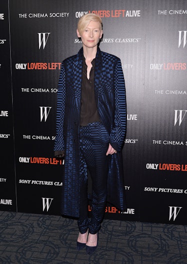 Tilda Swinton wearing a long blue blazer, and blue pants, all covered in black patterns