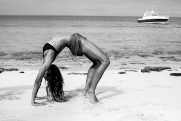 Model doing a bridge exercise on a beach in black and white 