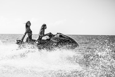 Two models riding a jet ski in black and white