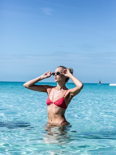 An influencer wearing a red bikini standing in the sea 