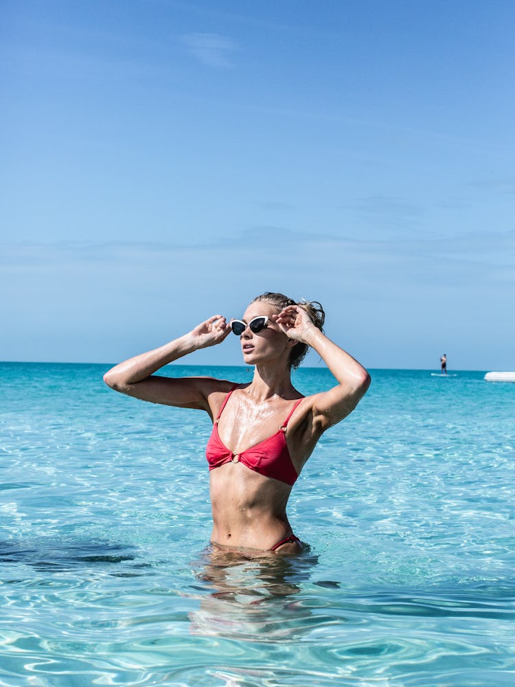 An influencer wearing a red bikini standing in the sea 