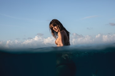 Alessandra Ambrosio walking in the sea while looking over her shoulder at the camera
