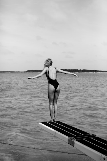 Model jumping off a diving board in black and white 