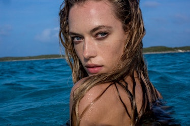 Blonde model in a water, with a wet hair over her face while looking straight into the camera 