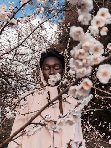 “In the Youth of Our Fury” photo essay part by Margaret Zhang with a woman standing under a blossom ...