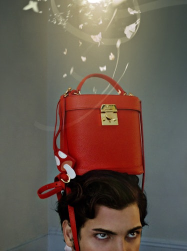 A red bag placed on the head of a brunette man by Bryan Huynh