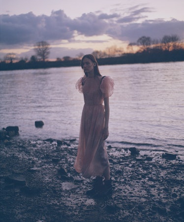A woman in a peach tulle dress walking near a lake by Fernando Uceda
