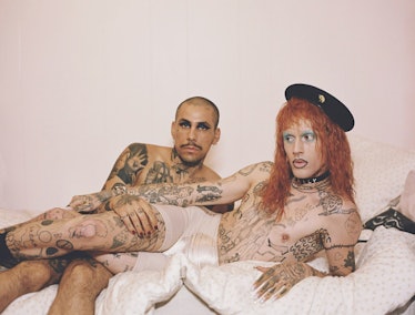 Two people covered with tattoos lying and posing in a bed by Harry Eelman