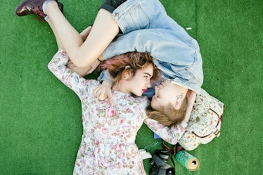 Two women lying on a green surface and looking at each other by Harry Eelman