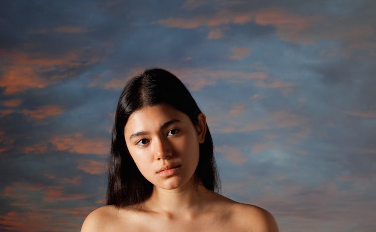 A portrait of a brunette woman with a cloud painting behind her by Michael Beckert