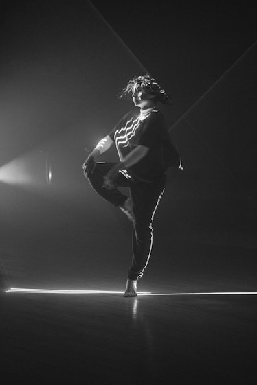 A woman in a shirt and pants dancing in black and white by Oliver Holms