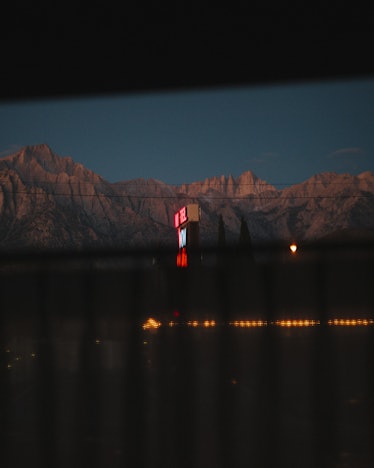 Mountains in the distance and street lights visible through a blurry fence by Roman Koval
