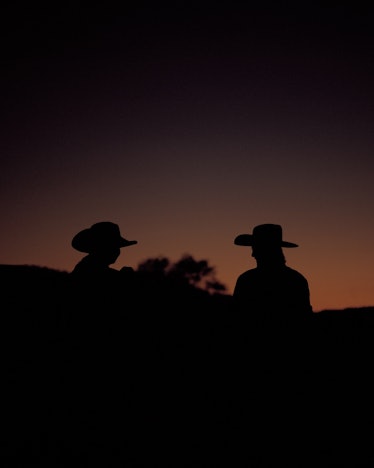 Two people with cowboy hats, darkened with the sunset visible in the background by Ryan Shorosky