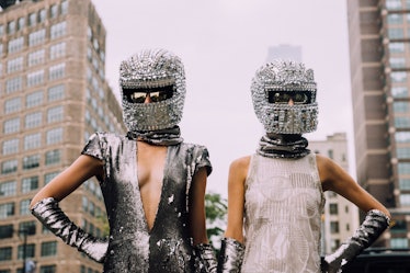 Two woman in silver and white dresses wearing rhinestone embellished helmets by Sean Williams