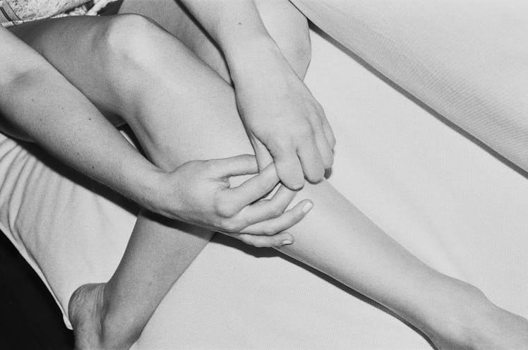 A close-up of a woman's legs while holding her hands over them by Simbarashe Cha