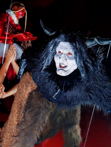 A person in a costume with a brown fur bodysuit and a white mask with black horns by Zak Krevitt