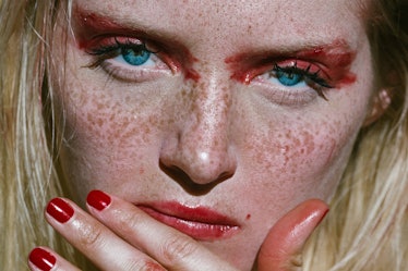A close-up portrait of a blue-eyes woman with red nails, lips and eyeshadow by Corey Tenold