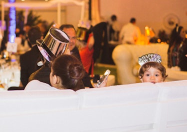 A little kid with a "happy new year" crown looking straight at the camera at the New Year’s Eve Bash...