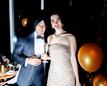 A man in a turban and suit posing for a photo with a woman in a beige sequin gown