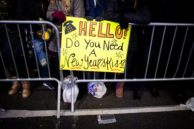 A person holding a sign reading: 'Hello! Do you need a New Year's Kiss?'