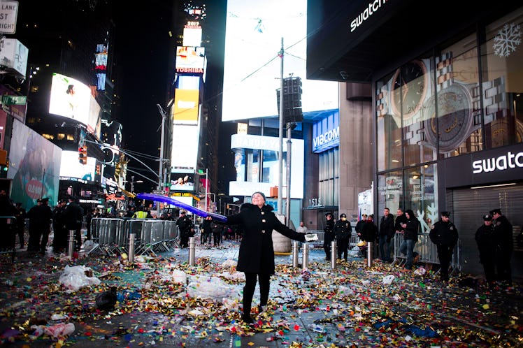 A person holding a blue balloon standing at Times Square after New Year's Eve 2017 celebration.