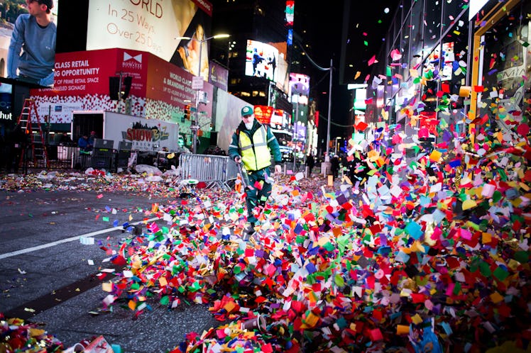 A person blowing confetti off the street on Times Square.