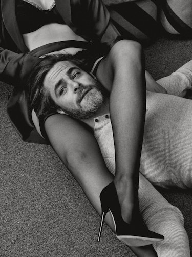 Chris Pine lying with a woman's legs wrapped around his neck 