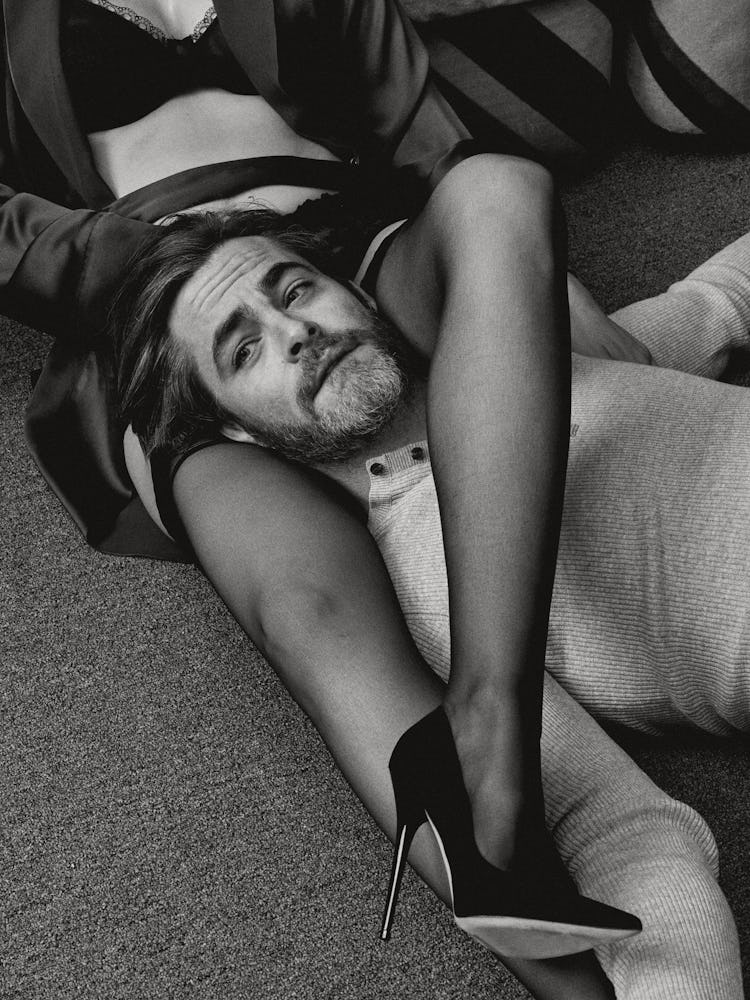 Chris Pine lying with a woman's legs wrapped around his neck 