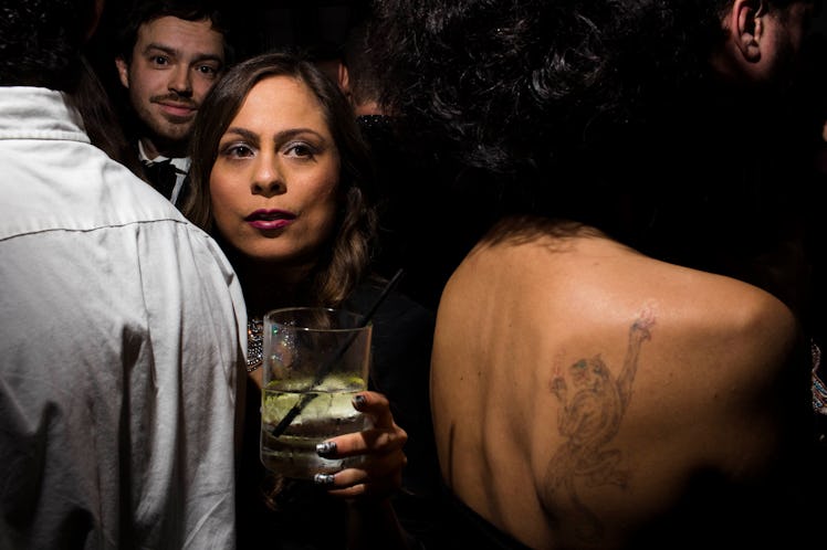 A woman trying to pass through the crowd with a drink in her hand at the party 