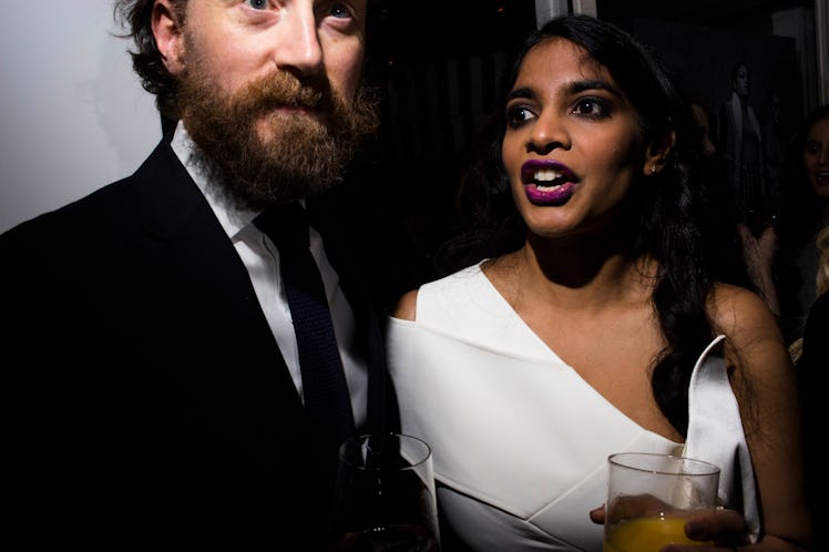 A man in a suit and a woman in a white one-shoulder dress looking in different directions at W's Gol...