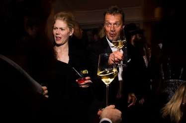 A man and woman dancing with their drinks and raising their glasses to other people at the party 