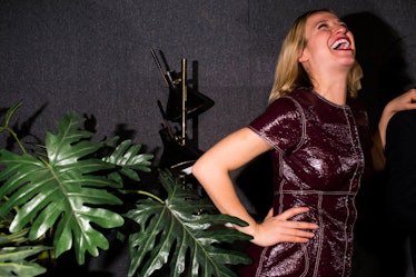 A blonde woman in a shiny purple dress laughing next to a green plant at W's Golden Globes party 