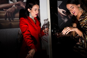 A woman in a red dress looking stunned at another woman's ring at W's Golden Globes party 