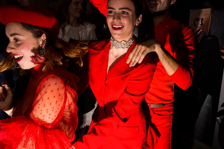Two women in red dresses and a man in a red sweater and pants doing the dancing train at W's party 