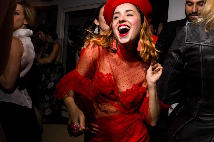 A woman in a sheer red dress and red hat dancing at W's Golden Globes party 
